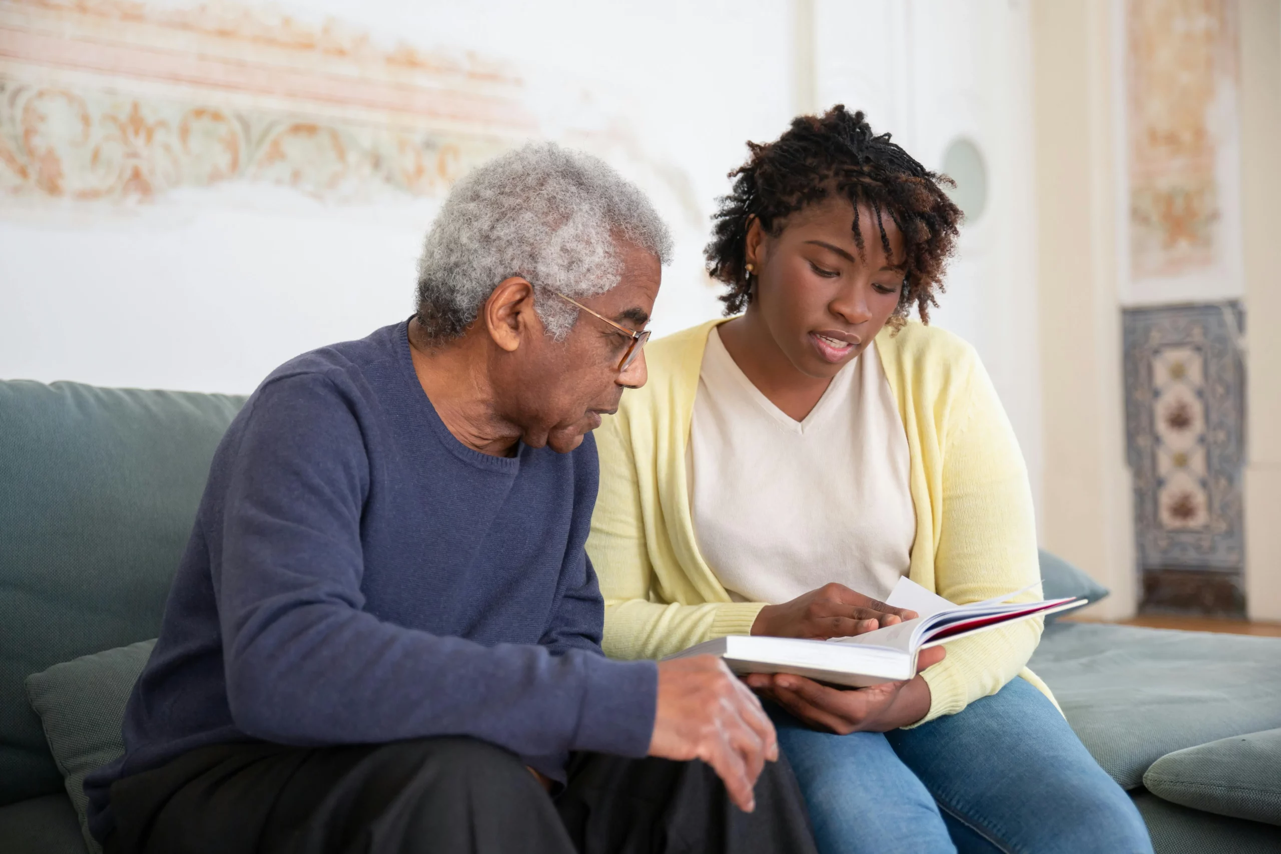 A professional caregiver warmly speaking with an elderly client in a comfortable home setting